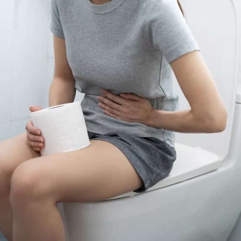 Woman sitting on the toilet with stomach discomfort.